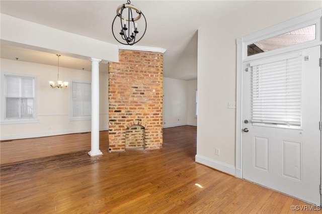 unfurnished living room with hardwood / wood-style flooring, a chandelier, and decorative columns