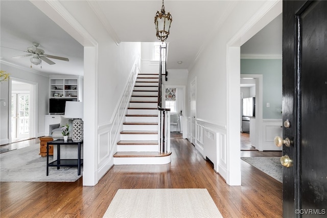 stairs featuring crown molding, hardwood / wood-style floors, ceiling fan, and built in shelves