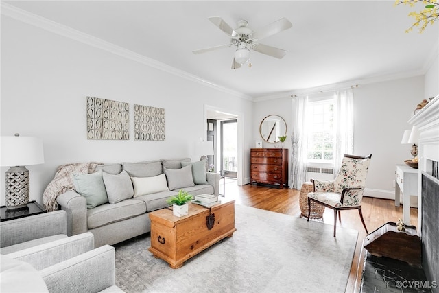 living room with crown molding, ceiling fan, a fireplace, and light hardwood / wood-style floors