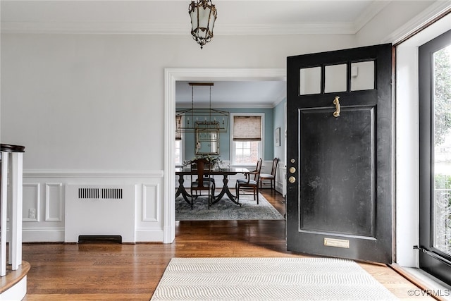 entryway with dark hardwood / wood-style flooring, ornamental molding, and an inviting chandelier