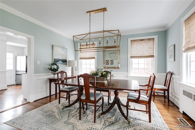 dining area featuring hardwood / wood-style floors, crown molding, and radiator heating unit