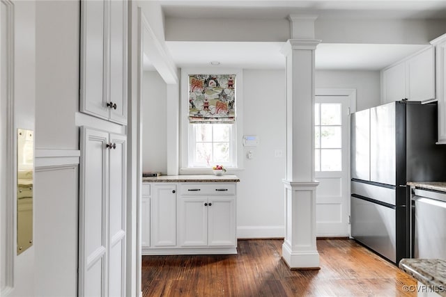 kitchen with appliances with stainless steel finishes, dark hardwood / wood-style floors, decorative columns, white cabinets, and light stone countertops