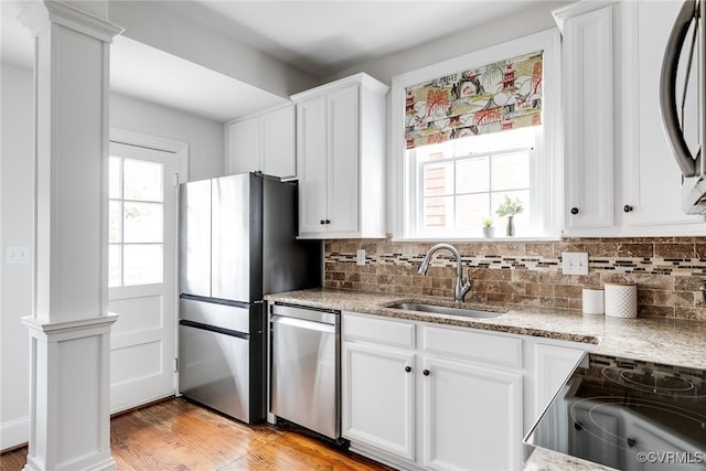 kitchen featuring white cabinetry, stainless steel appliances, sink, and light stone counters