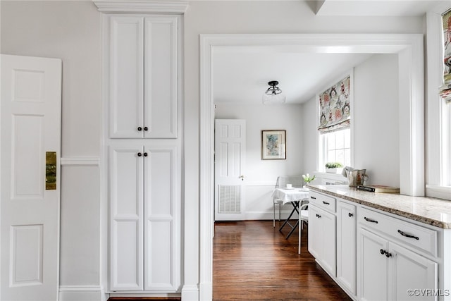 kitchen featuring dark hardwood / wood-style floors, white cabinets, and light stone counters