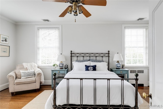 bedroom with radiator, ornamental molding, hardwood / wood-style floors, and ceiling fan