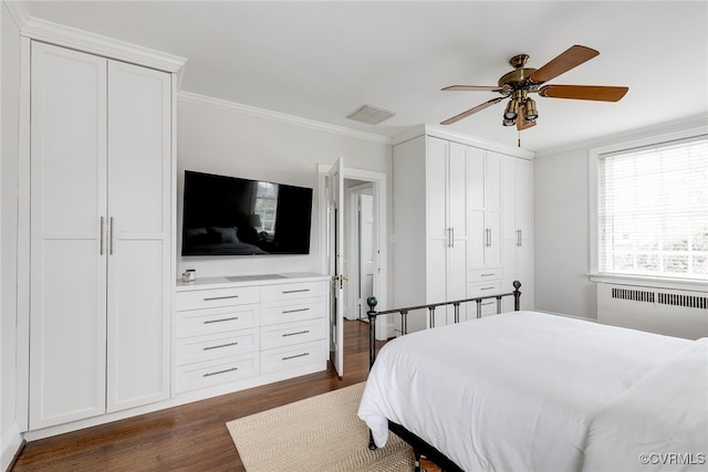 bedroom featuring dark wood-type flooring, radiator heating unit, ornamental molding, and ceiling fan