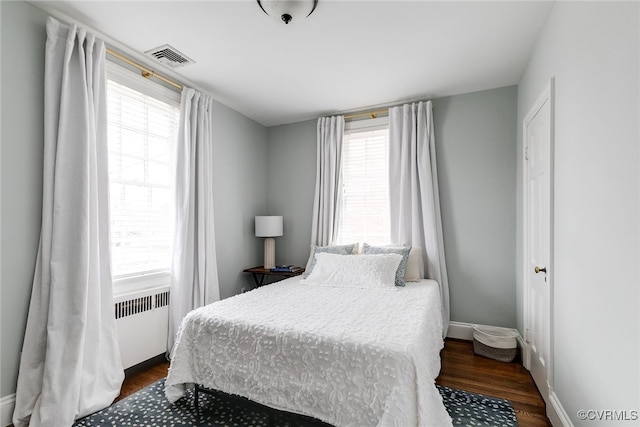 bedroom with dark wood-type flooring and radiator heating unit