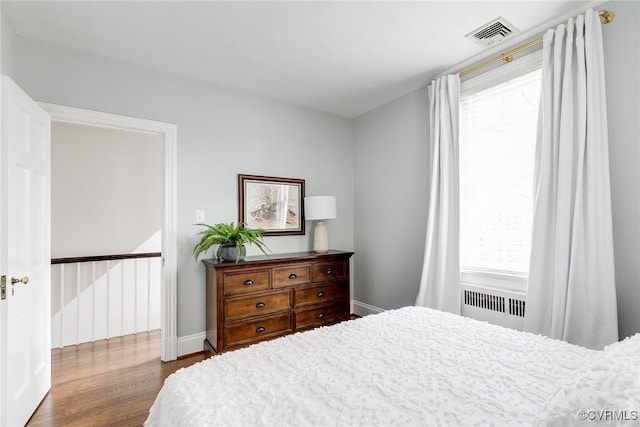 bedroom featuring hardwood / wood-style flooring and radiator heating unit