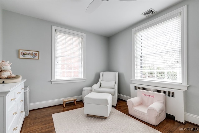 sitting room with ceiling fan, radiator heating unit, and dark hardwood / wood-style flooring