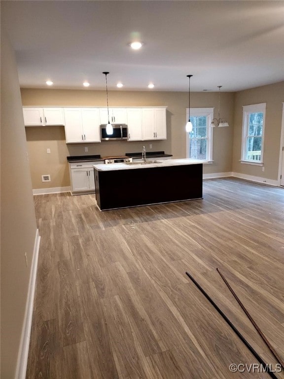 kitchen with white cabinetry, sink, a center island with sink, and decorative light fixtures