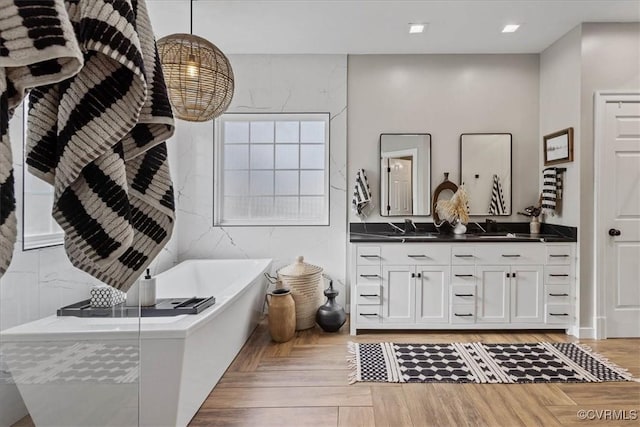 bathroom featuring vanity, parquet floors, and a bathtub