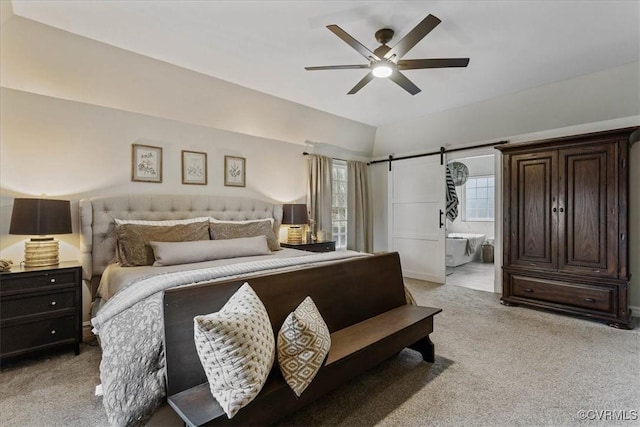 bedroom with ceiling fan, light colored carpet, a barn door, and ensuite bath