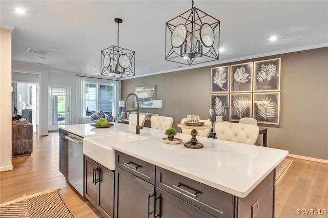 kitchen featuring an island with sink, stainless steel dishwasher, an inviting chandelier, and decorative light fixtures