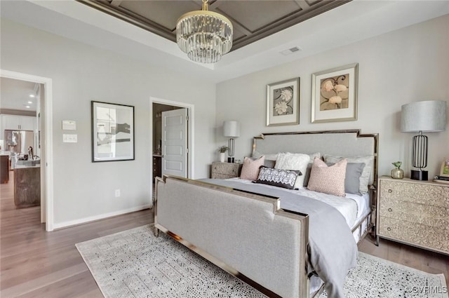 bedroom with wood-type flooring, stainless steel fridge, a notable chandelier, and crown molding