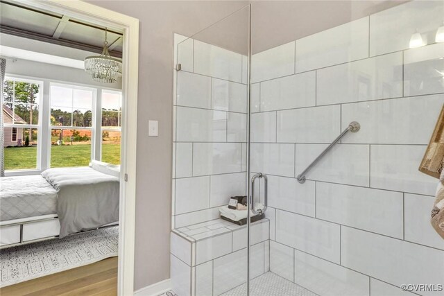 bathroom featuring wood-type flooring, a shower with door, and a notable chandelier