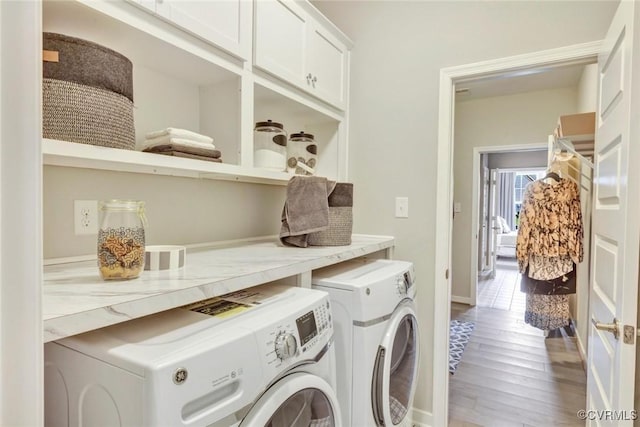 clothes washing area featuring cabinets, independent washer and dryer, and wood-type flooring