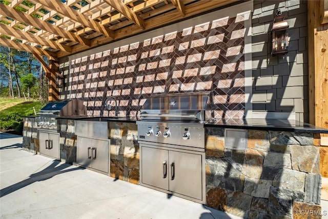 view of patio / terrace featuring a grill, a pergola, and exterior kitchen