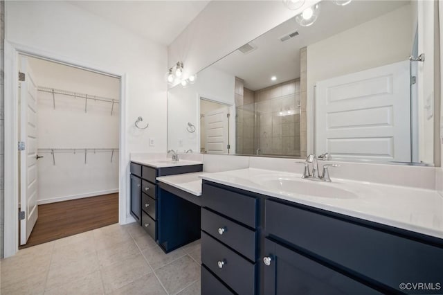 bathroom with a shower with door, vanity, and tile patterned floors