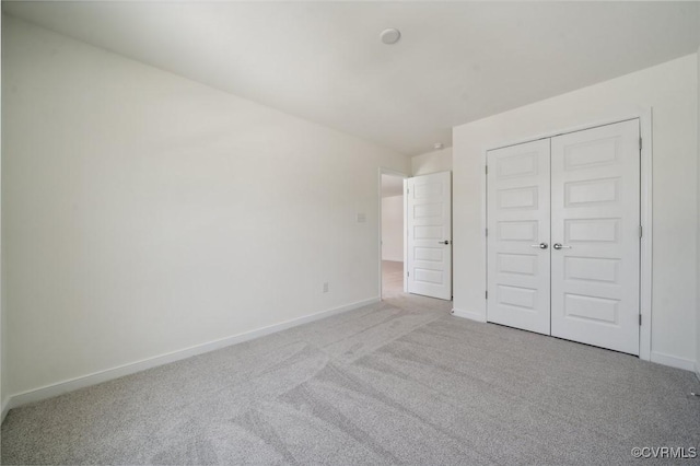 unfurnished bedroom featuring light colored carpet and a closet