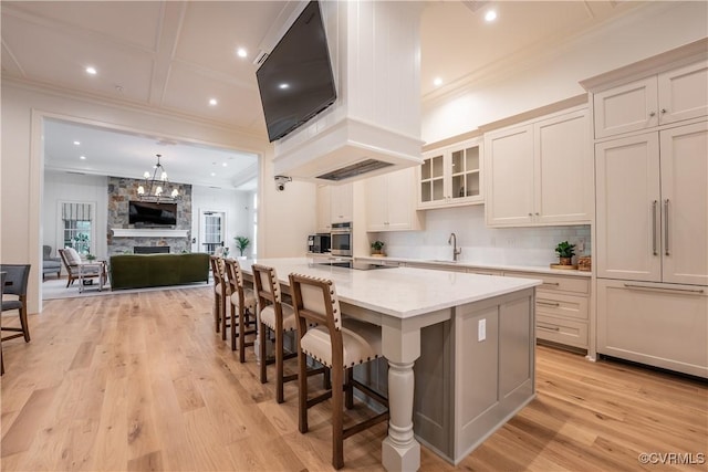 kitchen featuring light stone counters, white cabinetry, a breakfast bar, and a center island with sink