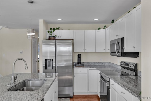 kitchen with pendant lighting, sink, appliances with stainless steel finishes, white cabinetry, and light stone counters