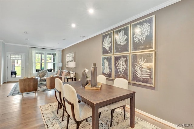 dining area with crown molding and light wood-type flooring