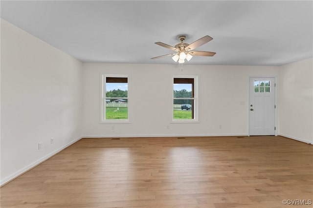 spare room featuring a wealth of natural light, ceiling fan, and light wood-type flooring