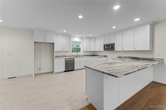 kitchen with white cabinetry, light stone counters, and appliances with stainless steel finishes