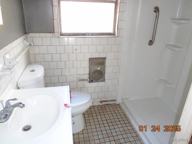 bathroom featuring tile patterned floors, toilet, a shower, tile walls, and vanity