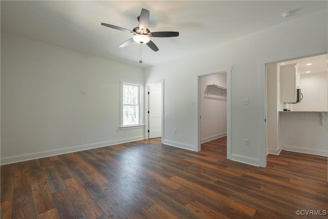 unfurnished bedroom with dark wood-type flooring, ceiling fan, a spacious closet, and a closet