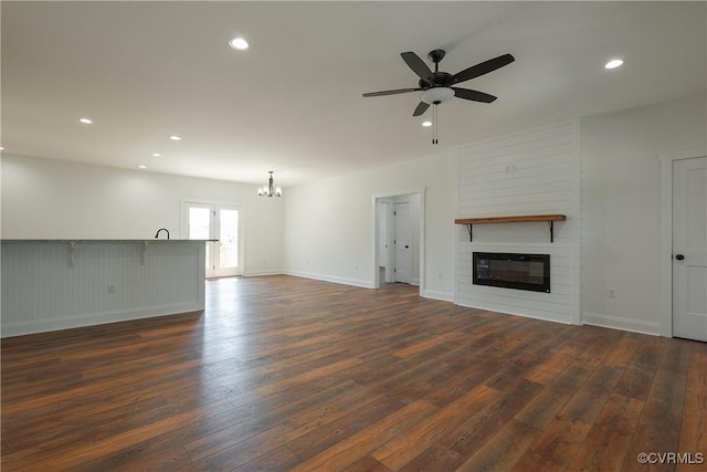 unfurnished living room with dark hardwood / wood-style floors, a fireplace, and ceiling fan with notable chandelier