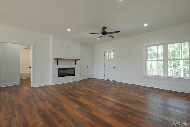 unfurnished living room featuring ceiling fan, dark hardwood / wood-style flooring, and a large fireplace