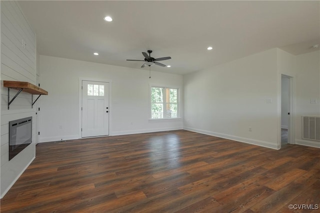 unfurnished living room with ceiling fan, a fireplace, dark hardwood / wood-style flooring, and heating unit