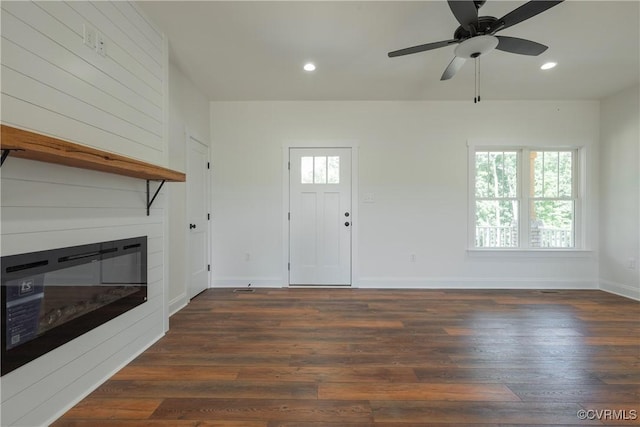 unfurnished living room featuring ceiling fan, dark hardwood / wood-style floors, and a fireplace