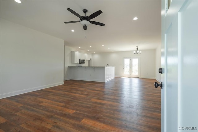 unfurnished living room with dark wood-type flooring, ceiling fan with notable chandelier, and french doors