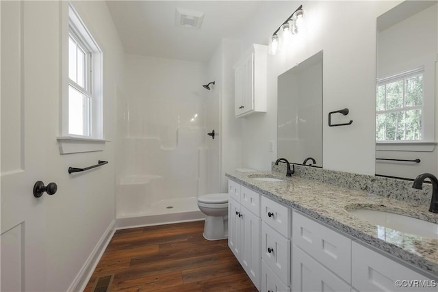 bathroom with hardwood / wood-style flooring, vanity, toilet, and a shower