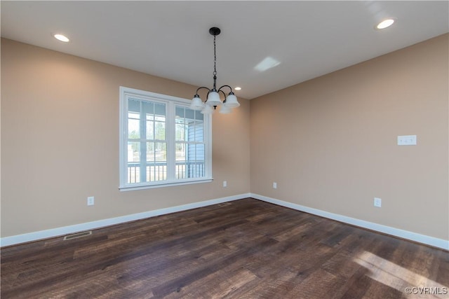 spare room featuring an inviting chandelier and dark wood-type flooring