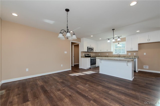 kitchen featuring pendant lighting, white cabinetry, stainless steel appliances, light stone counters, and a kitchen island