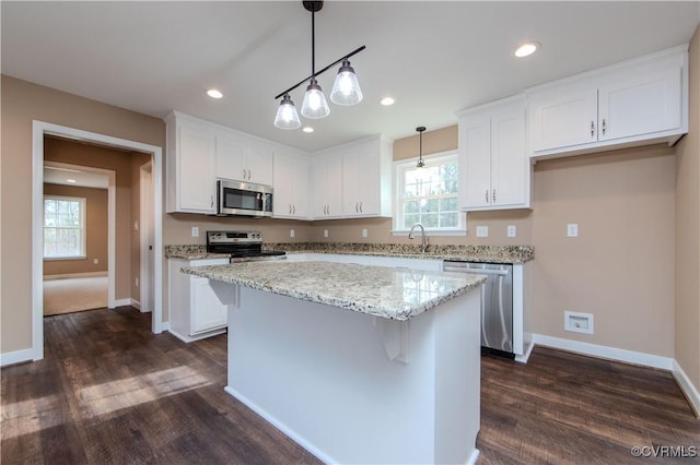 kitchen featuring appliances with stainless steel finishes, decorative light fixtures, a center island, and white cabinets