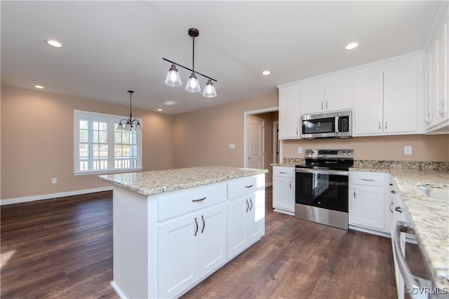 kitchen featuring stainless steel appliances, white cabinetry, a kitchen island, and decorative light fixtures