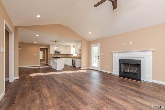 unfurnished living room featuring lofted ceiling, dark wood-type flooring, and ceiling fan