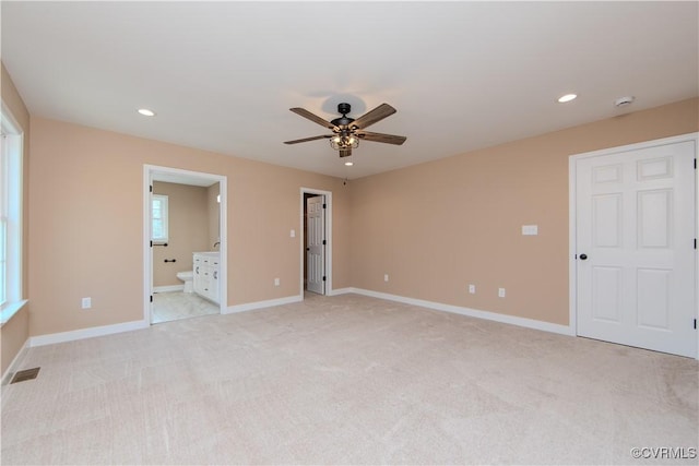 unfurnished bedroom with ensuite bathroom, light carpet, and ceiling fan