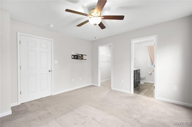 unfurnished bedroom featuring ensuite bathroom, a spacious closet, ceiling fan, light carpet, and a closet