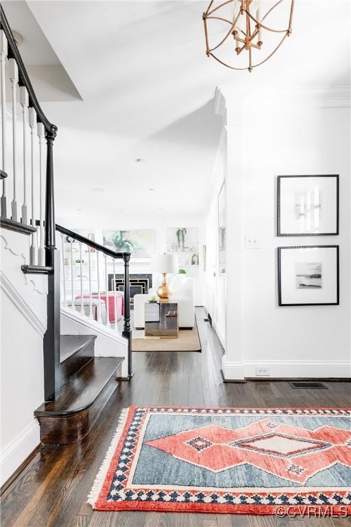 stairway featuring hardwood / wood-style flooring, ornamental molding, a notable chandelier, and built in shelves