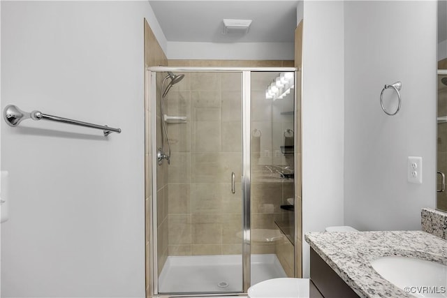 bathroom with walk in shower, vanity, and toilet