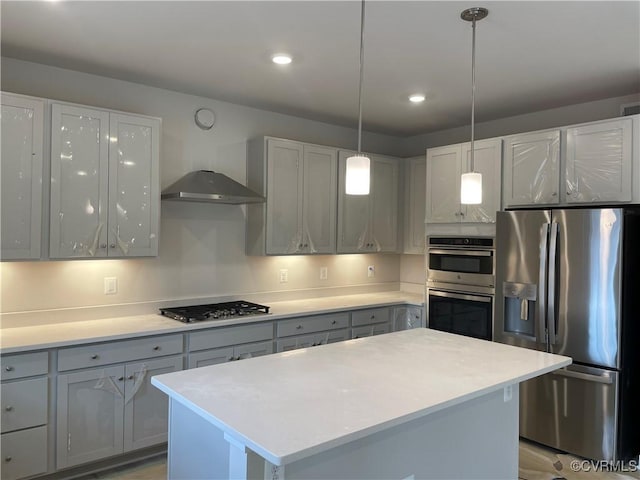 kitchen with gray cabinets, appliances with stainless steel finishes, hanging light fixtures, extractor fan, and a kitchen island