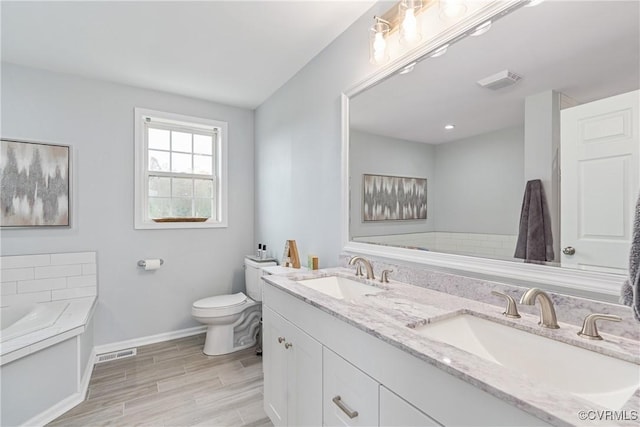 bathroom with vanity, wood-type flooring, a tub, and toilet