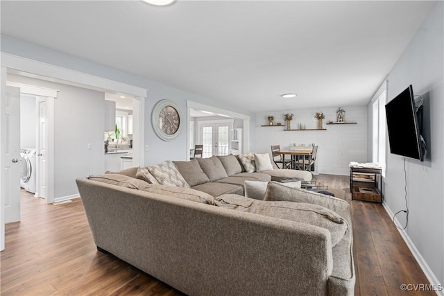 living room with plenty of natural light, washing machine and clothes dryer, dark hardwood / wood-style flooring, and french doors