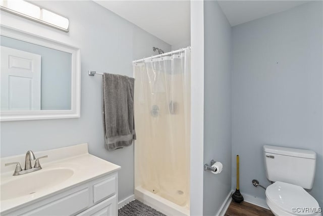 bathroom with hardwood / wood-style floors, vanity, toilet, and walk in shower