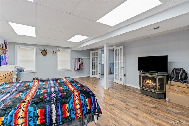 bedroom with a drop ceiling, wood-type flooring, and french doors